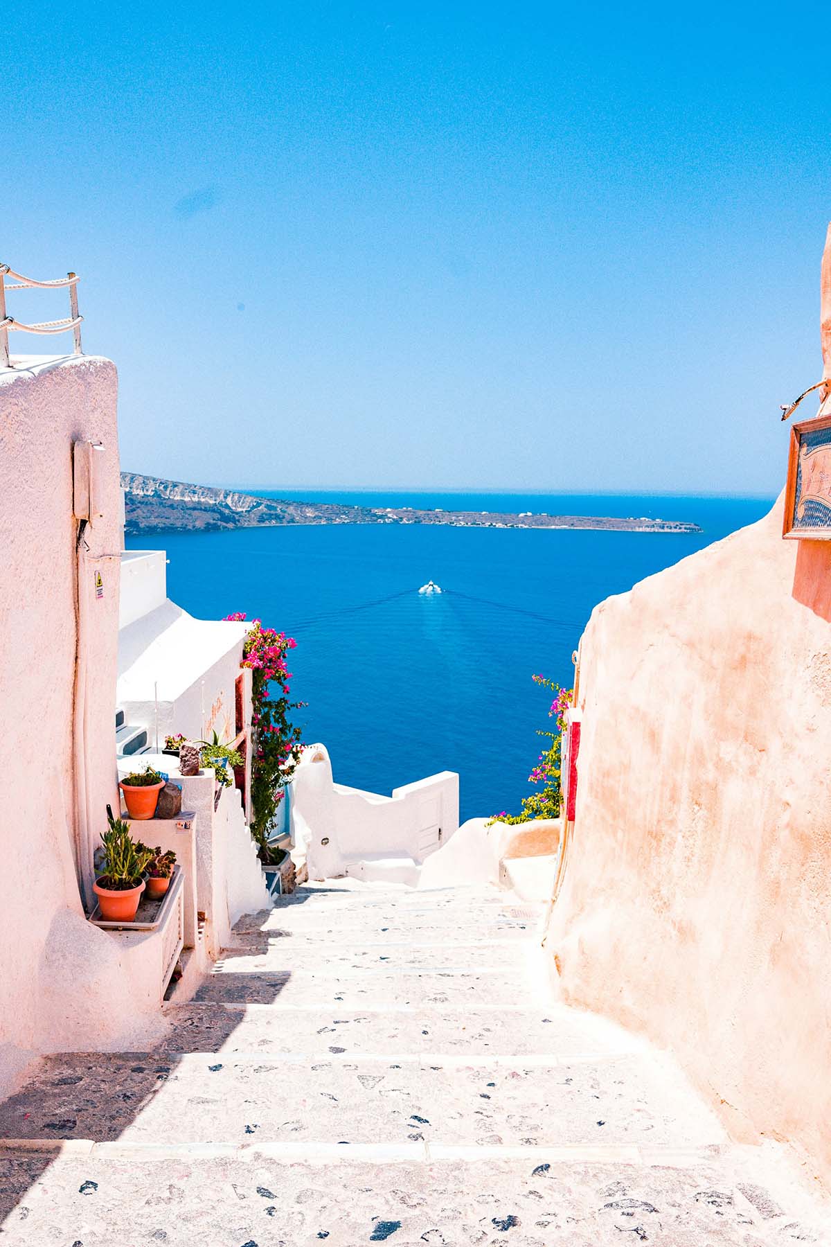 Oia Santorini narrow cobblestone lane with white buildings and blue sea