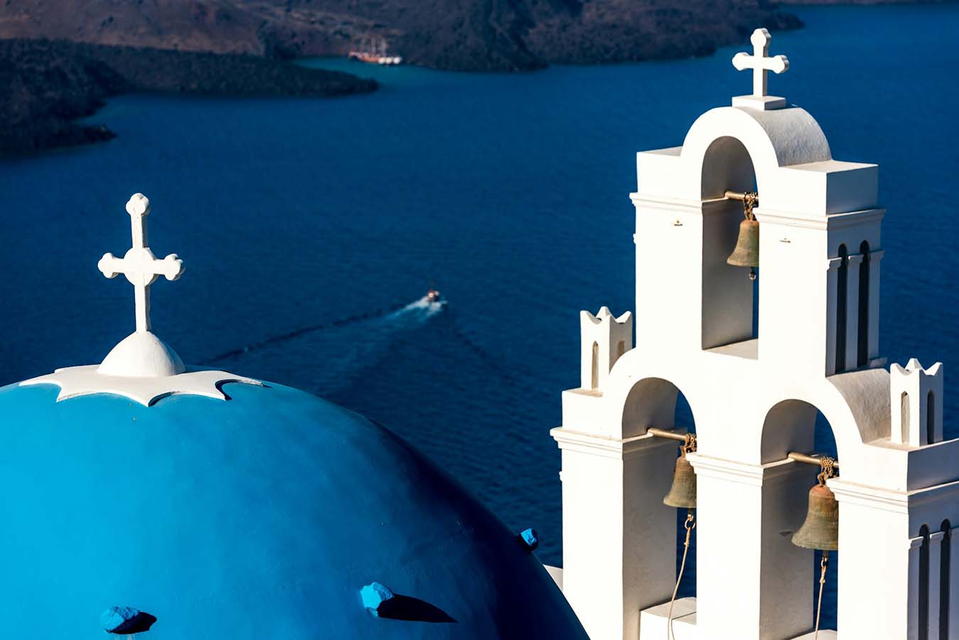 Santorini caldera boat tour with white church dome and blue sea